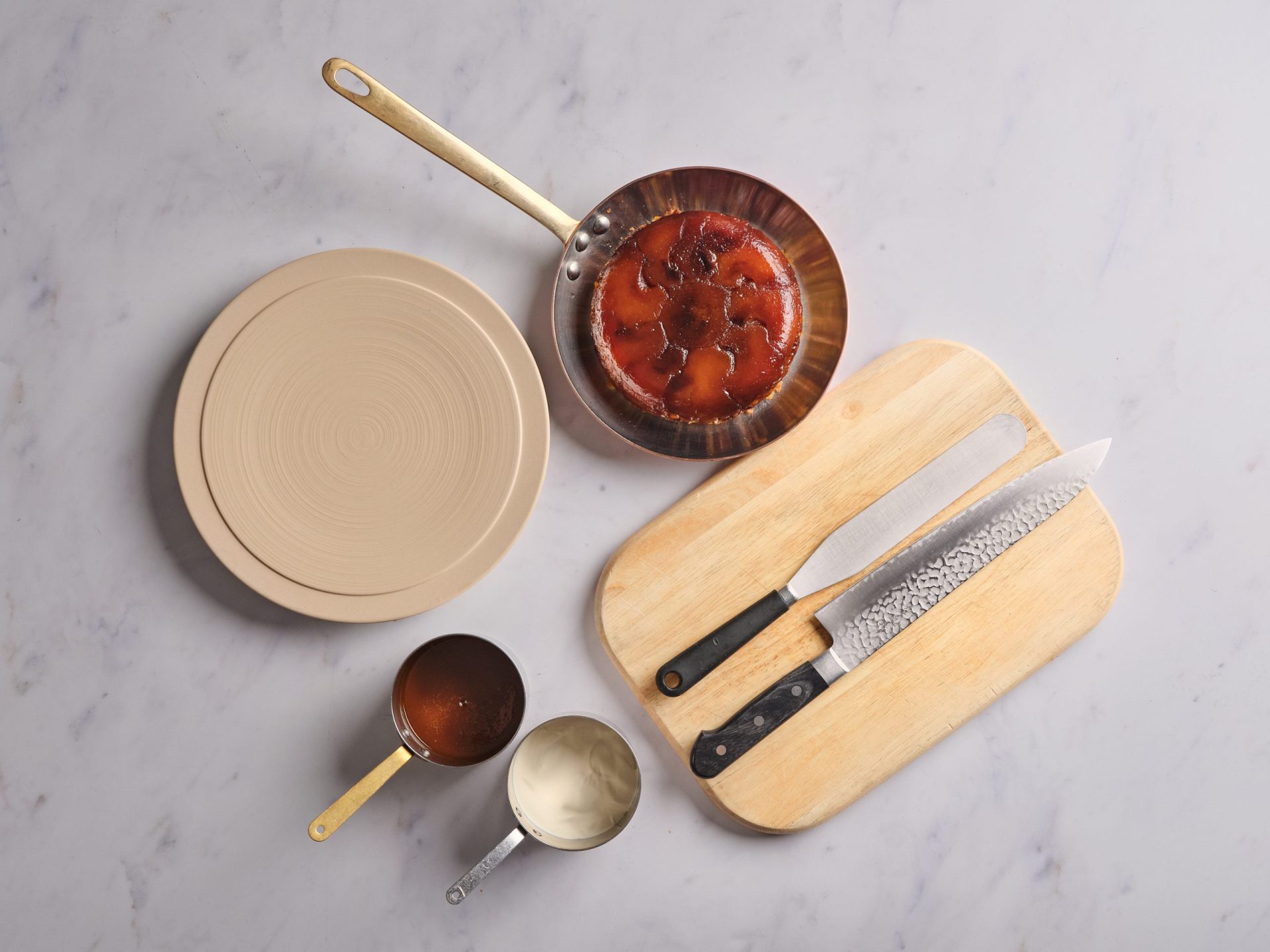 Cooking ingredients and tools flatlay with copper pot, wooden cutting board, knives and sauce pots