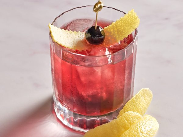 Red bespoke cocktail with citrus garnish at Wild Honey Bar