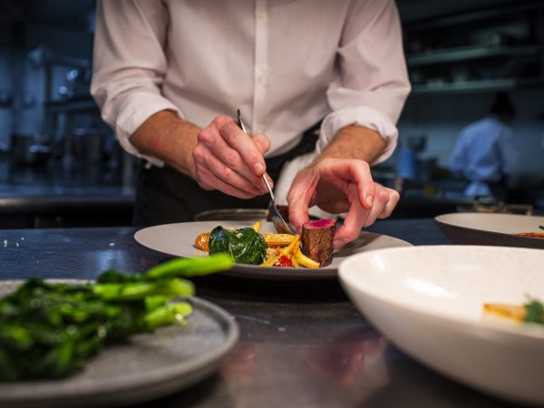Chef carefully plating a seasonal dish in the Wild Honey St James kitchen